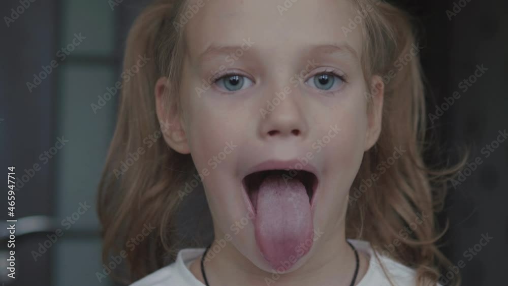 Child girl opens her mouth wide. child shows her teeth and mouth to dentist. mouth is wide open, tongue is stuck out as far as possible, with clear view of tongue and soft palate