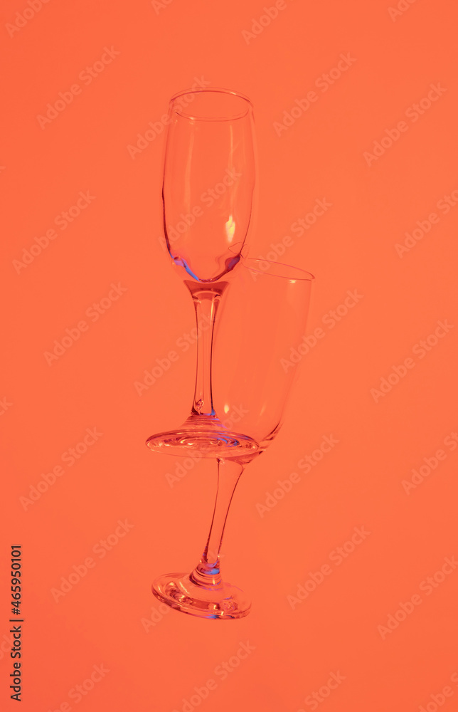 two glasses of champagne with neon orange lights. modern futurism 2022 year background. minimalism. surrealism. creative decoration idea