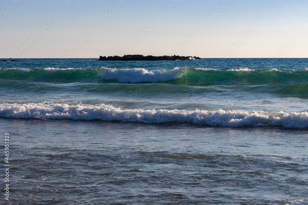 Turquoise sea wave rolls onto the beach