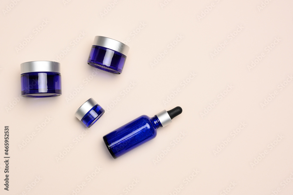glass cosmetic blue bottles with a pipette and jar on a beige background. Cosmetics SPA branding mockup glass cosmetic blue bottles with a pipette and jar on a beige background. Cosmetics SPA branding mockup