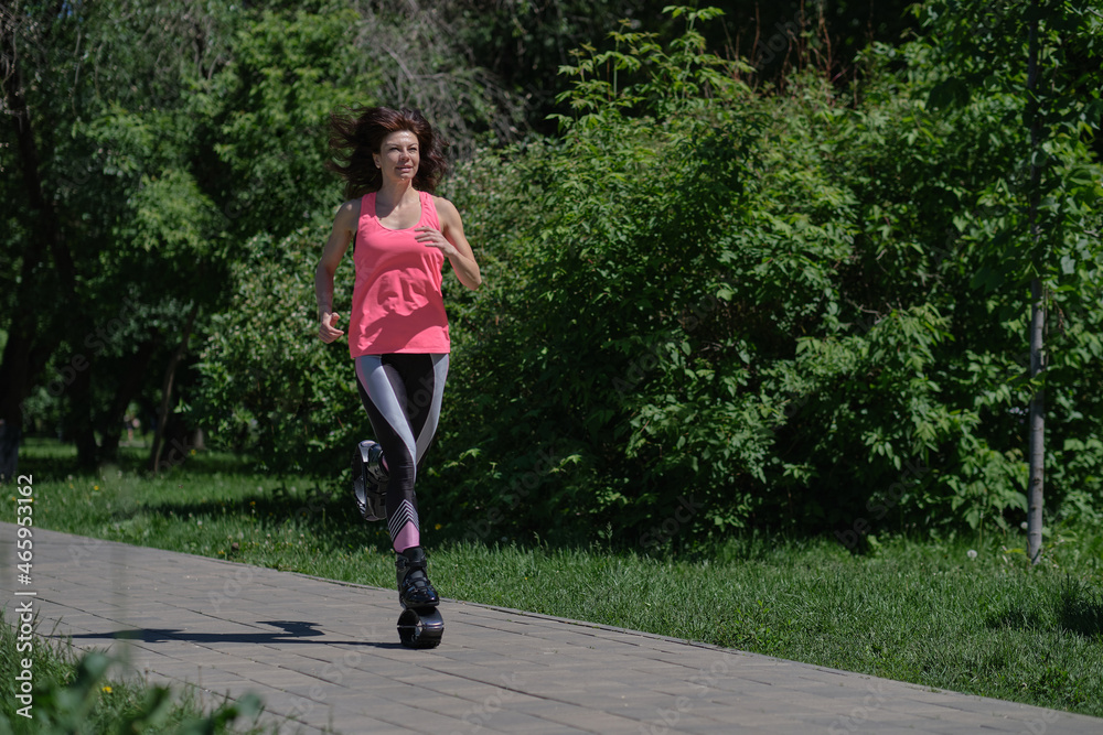 beautiful woman runs along the path in the park, legs in kangoo jumping shoes. women training Kangoo Jumping beautiful woman runs along the path in the park, legs in kangoo jumping shoes. women training Kangoo Jumping