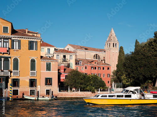 Grand Canal in Venice, Italy. Passenger vaporetto boat and historic buildings with church bell tower, belfry. Venetian passenger water transport, logos removed for commercial use.
