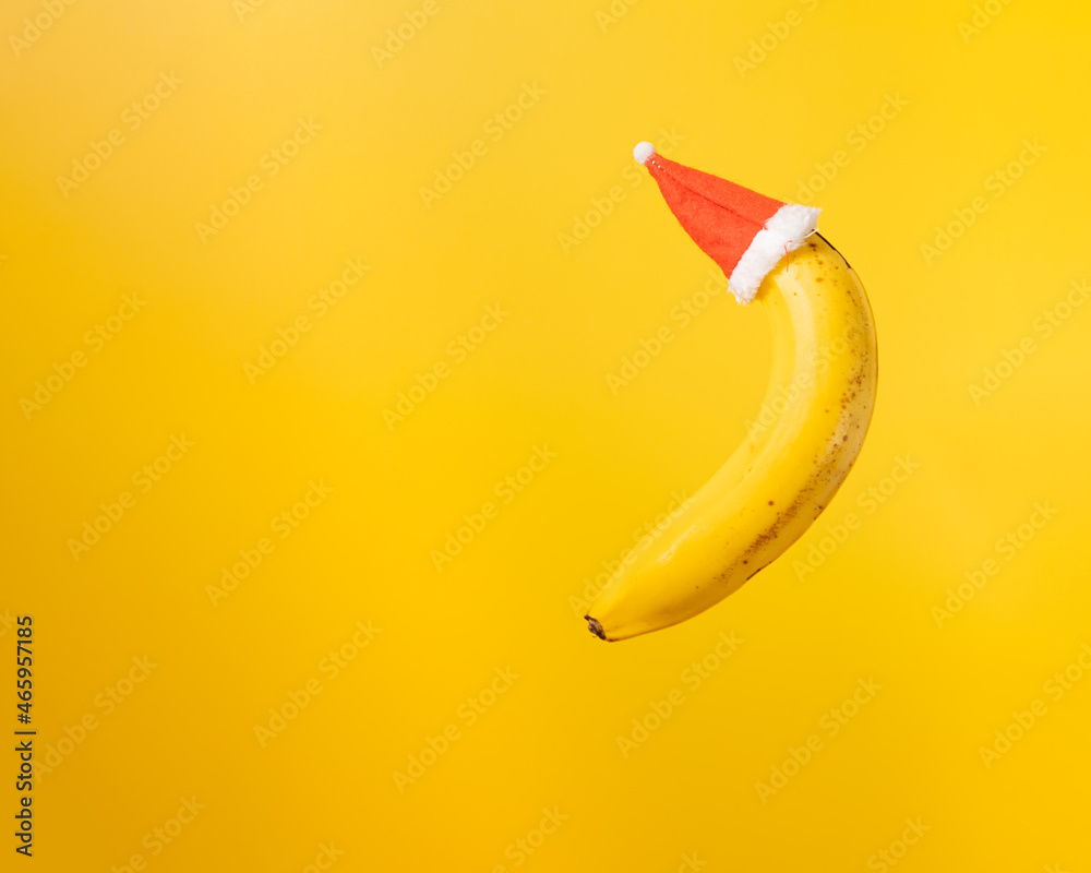 Banana with christmas hat on yellow background