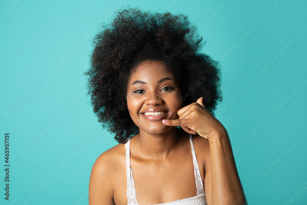 Cheerful young woman with afro hairstyle on blue background with hand gesture Cheerful young woman with afro hairstyle on blue background with hand gesture