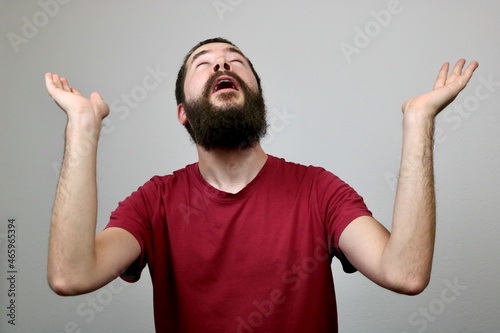 Young bearded caucasian man raising arms while praying  photo