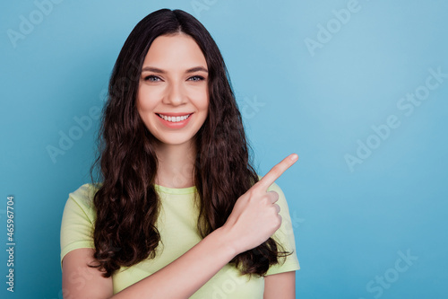 Portrait of cheerful adviser lady indicate forefinger empty space toothy beaming smile on blue background