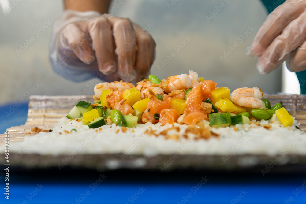 Manos preparando un rollo de Uramaki 