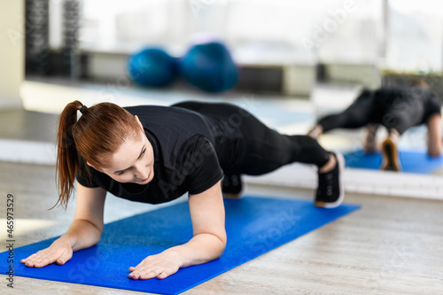 Girl doing the plank in the gym. Middle-aged Fitness Woman. Sport and healthy lifestyle concepts