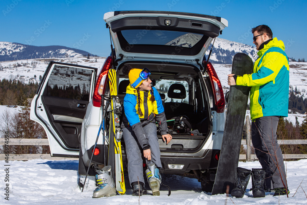 man and woman dressing into ski equipment near suv car man and woman dressing into ski equipment near suv car