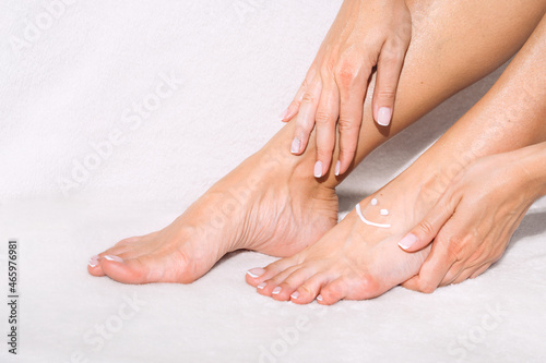 Woman applying legs cream, lotion or moisturizer. Skin care. Beautiful woman feet with cream