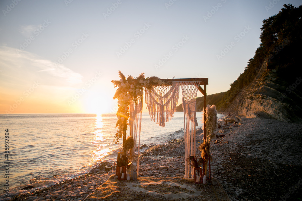 arch design with flowers and macrame for a photo shoot of a wedding ceremony at sunset on the seashore