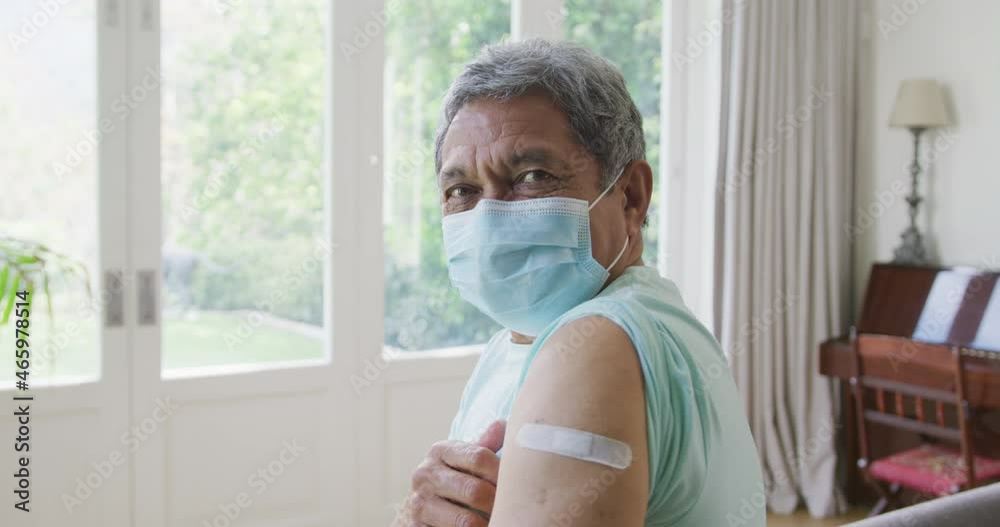 Portrait of senior man wearing protective face mask showing covid vaccine bandage on shoulder Portrait of senior man wearing protective face mask showing covid vaccine bandage on shoulder