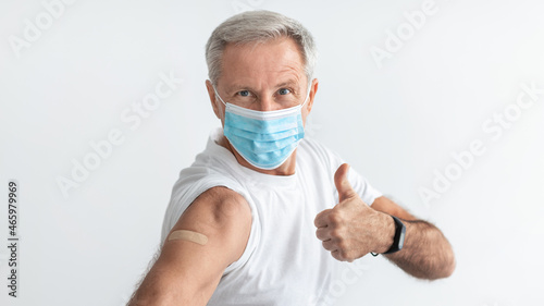 Vaccinated Senior Man Gesturing Thumbs-Up On Gray Background  Wearing Mask