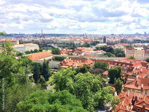 Overview of the landscape in Prague, Czech Republic. In the photo you can see the roofs of many buildings and greenery. The architecture of the buildings is very unique to the city of Prague.