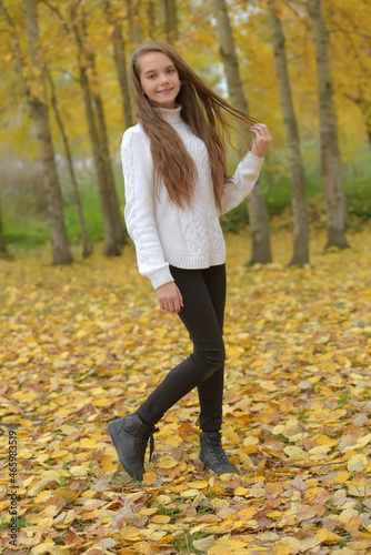 girl brunette child in white sweater in autumn in the park