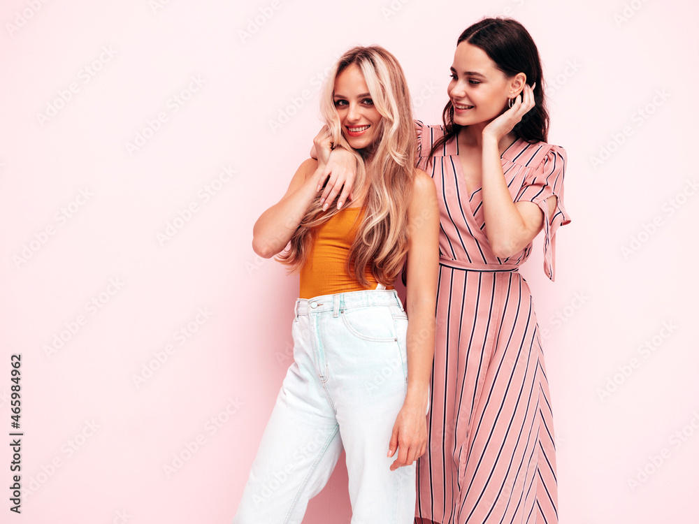 Two young beautiful smiling brunette hipster female in trendy summer clothes. Sexy carefree women posing near pink wall. Positive models having fun. Cheerful and happy Two young beautiful smiling brunette hipster female in trendy summer clothes. Sexy carefree women posing near pink wall. Positive models having fun. Cheerful and happy