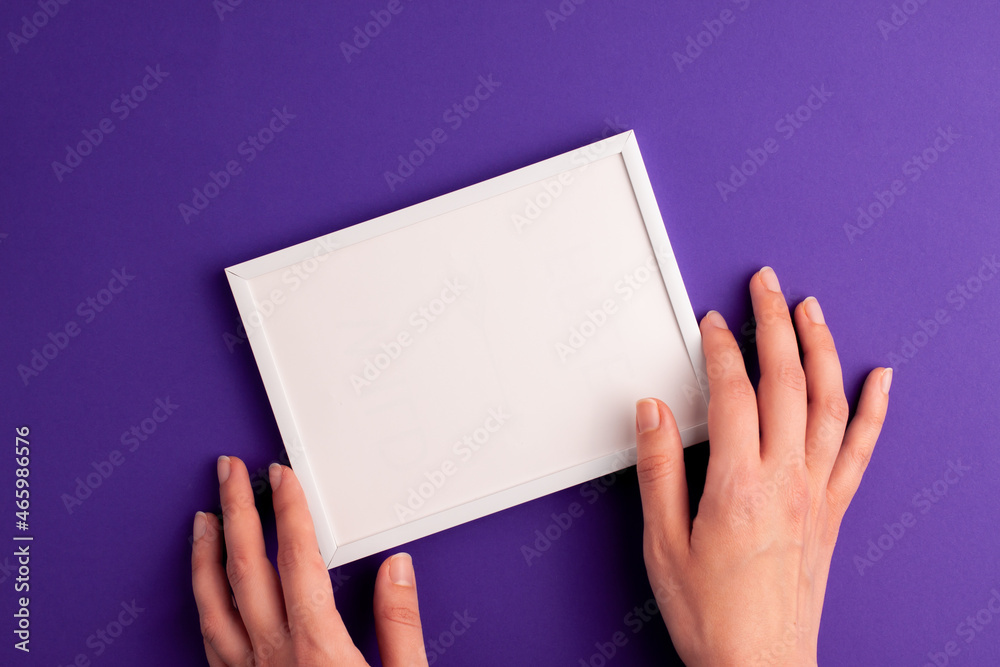 Mockup white frame with white paper inside and human hands on it on vibrant purple background. Halloween holiday presents happy birthday concept with space for your text template flat lay Mockup white frame with white paper inside and human hands on it on vibrant purple background. Halloween holiday presents happy birthday concept with space for your text template flat lay