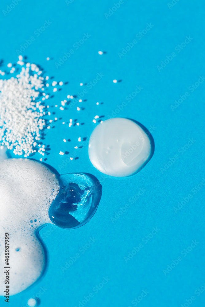 Cosmetic smears and drops. Appearance of the texture of the cream, oil and granules on a blue background. Natural skincare products. Beauty concept for face and body care