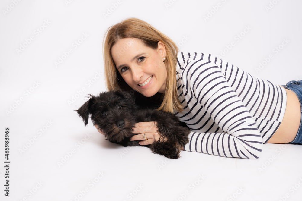 Young smiling woman lying on the floor embracing her dog isolated over white background. Young smiling woman lying on the floor embracing her dog isolated over white background.