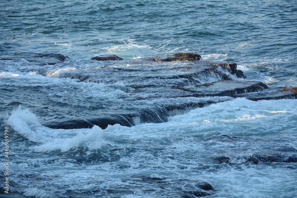 Obraz premium Sea Waves Crashing on the Rocks with White Foam. Swirling frothy foamy sea water over the rock near Akko(Acre) Israel