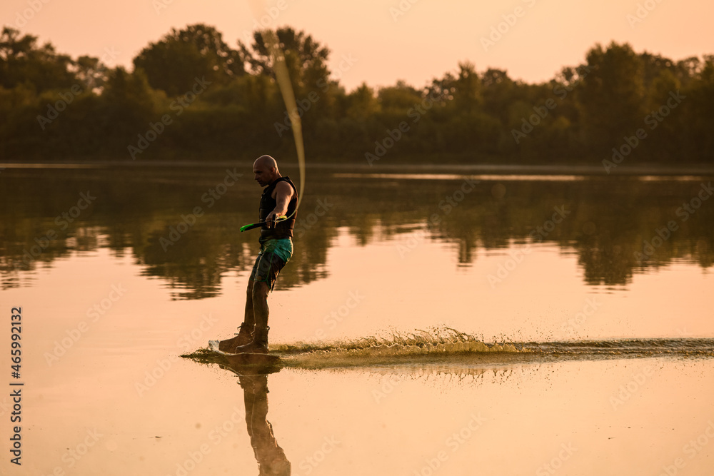 adult man engaged in water sport and skilfully balancing on water surface on a wakeboard adult man engaged in water sport and skilfully balancing on water surface on a wakeboard