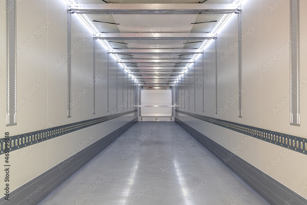 A big new empty refrigerated trailer inside. Inner space of the semi-trailer for transporting frozen food. Lighted cargo area for cargo placement