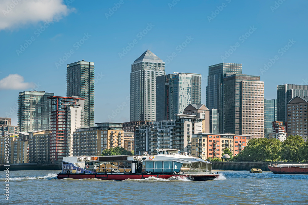 Fototapeta premium Scenic view on a sunny day with blue skies on office buildings, skyscrapers, River Thames, yacht, marina and residential buildings in the business district of London, UK.