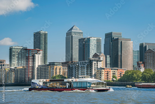 Scenic view on a sunny day with blue skies on office buildings, skyscrapers, River Thames, yacht, marina and residential buildings in the business district of London, UK.