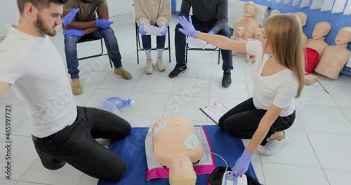 CPR training medical procedure workshop. Demonstrating chest compressions and use of AED automatic defibrillator on CPR doll. photo