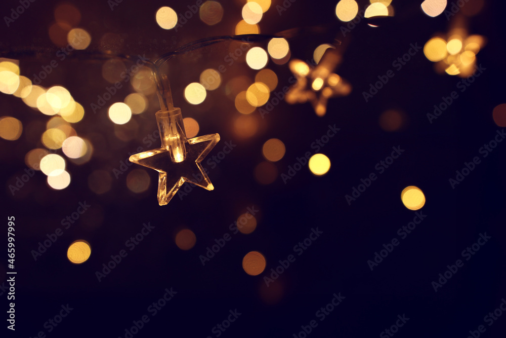 Christmas warm gold garland lights over dark background with glitter overlay - obrazy, fototapety, plakaty 