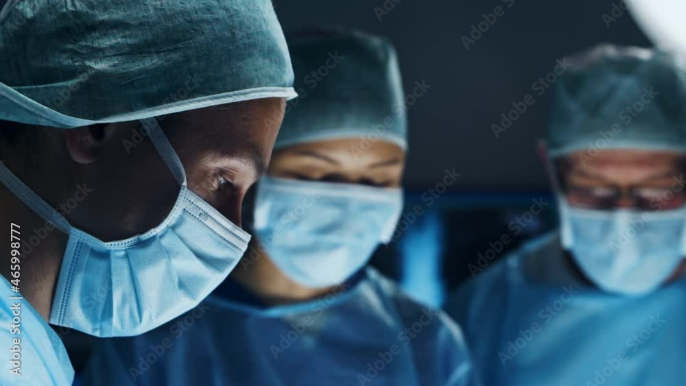 Multiracial team of professional medical surgeons performs the surgical operation in a modern hospital. Doctors are working to save the patient. Medicine, health, cardiology and transplantation.