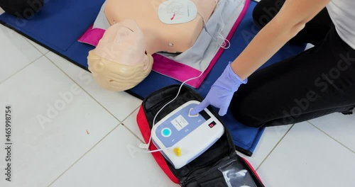 CPR training medical procedure workshop. Demonstrating chest compressions and use of AED automatic defibrillator on CPR doll photo