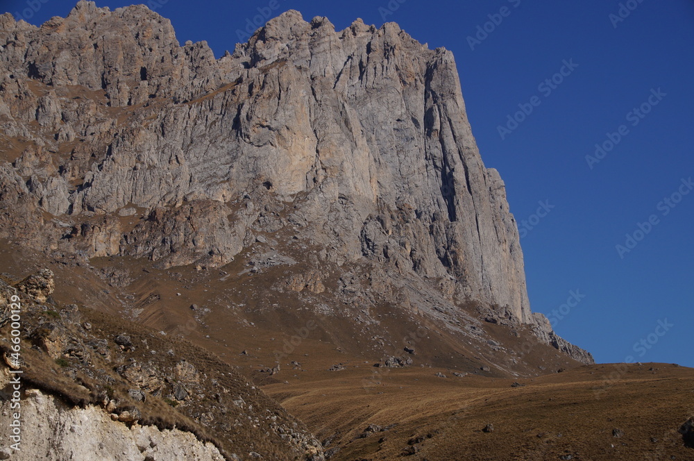 Mountain view on a clear autumn day. Mountains in Ingushetia. Landscape in the mountains in autumn. Rocks and trees in a mountainous area. Base jumping mountain.  
