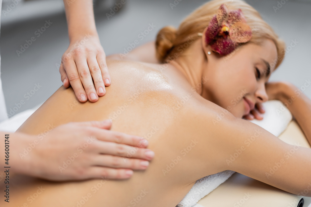 masseur rubbing massage oil into back of blurred client masseur rubbing massage oil into back of blurred client