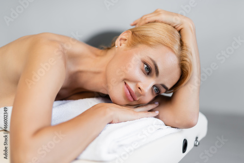 blonde woman smiling while lying on massage table in spa center