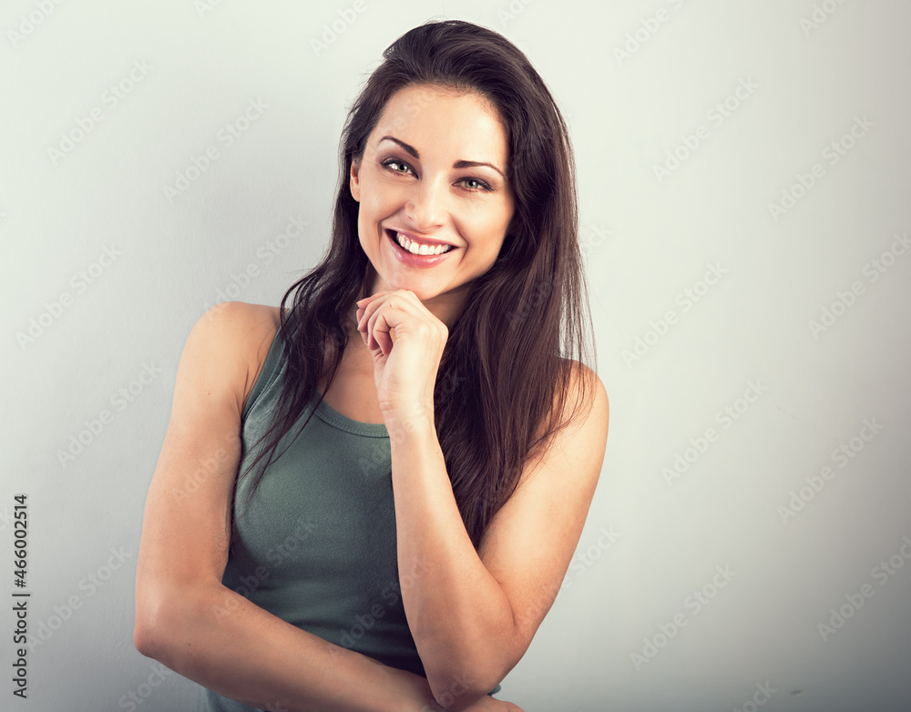 Beautiful young casual cute toothy smiling woman in green t-shirt on blue background. Closeup portrait