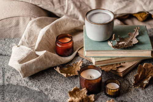old books, coffee cup and candles with dry oak leaves on a stone background