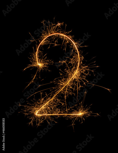 Digit 2 or two made of bengal fire, sparkler fireworks candle isolated on a black background. Party dark backdrop