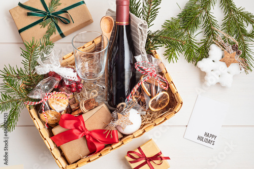 Refined Christmas gift basket for culinary enthusiats with bottle of wine and mulled wine ingredients. Corporate hamper or personal present for cooking lovers, foodies and gourmands. photo