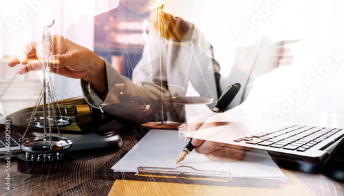 Justice and law concept.Male judge in a courtroom with the gavel, working with, computer and docking keyboard, eyeglasses, on table in morning light