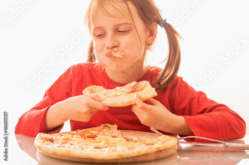 Funny image of beautiful child girl enjoys delicious slice of pizza  likes this taste  she has good appetite.