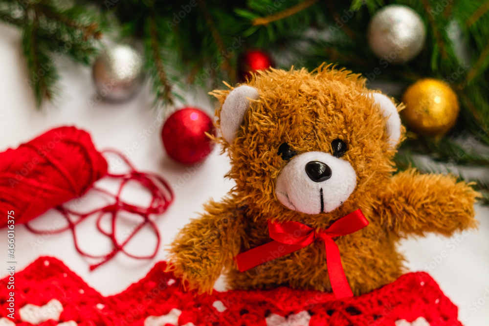 Teddy Bear with a red bow near the Christmas tree and bright balls. Teddy Bear with a red bow near the Christmas tree and bright balls.