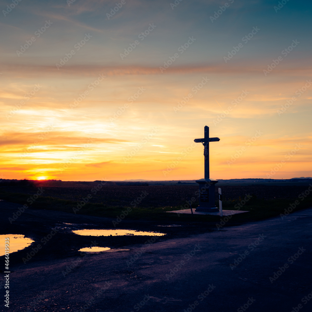 Colorful sunset in autumn in the hungarian countryside with a memorial cross statue