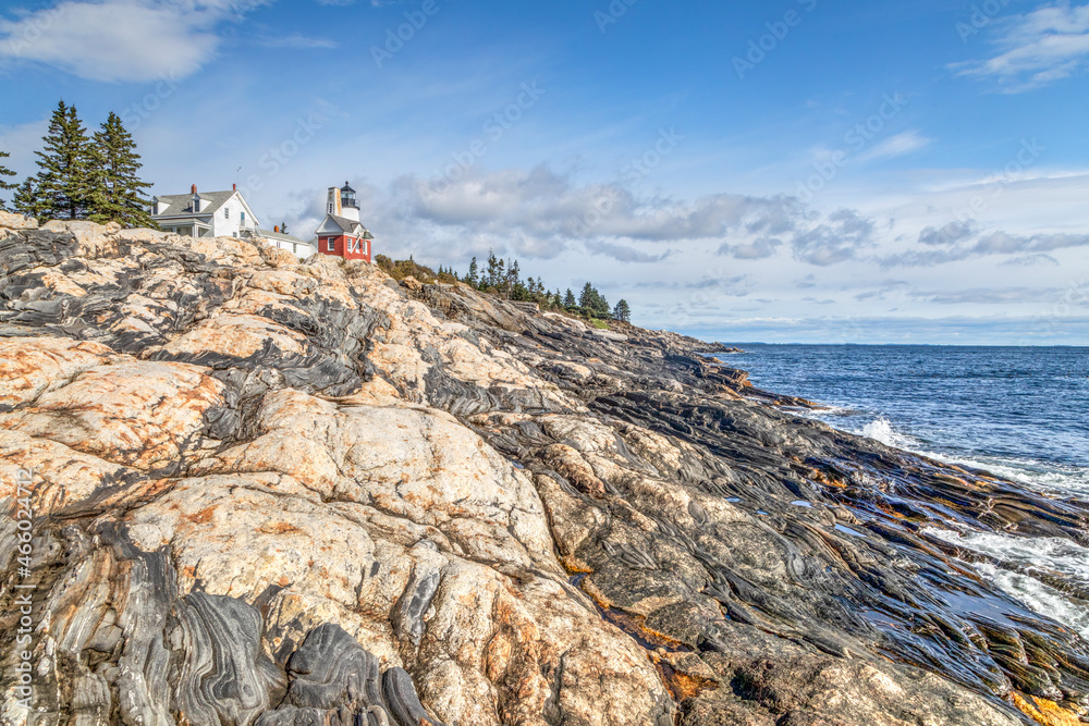 Obraz premium An interesting and beautiful rocky shore rises from the Atlantic Ocean below the historic landmark Pemaquid Point Lighthouse near the Down East community of Bristol, Maine.