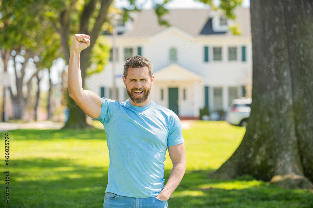 happy unshaven guy standing near new house celebrating success, neighborhood happy unshaven guy standing near new house celebrating success, neighborhood