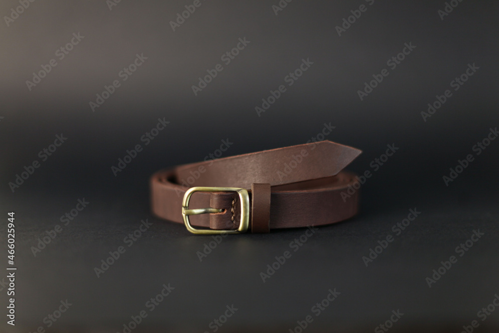 the eggplant-colored belt is handmade from genuine leather lying on a black background the eggplant-colored belt is handmade from genuine leather lying on a black background