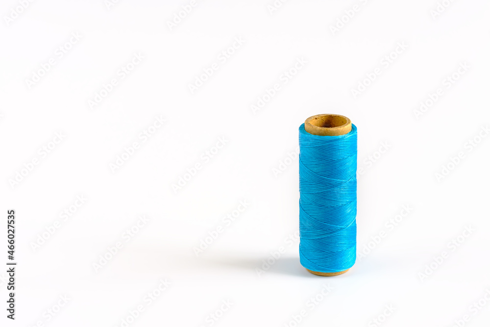 A coil of cyan thread. Spool of colored threads on a white background. Waxed sewing thread for leather crafts. A coil of cyan thread. Spool of colored threads on a white background. Waxed sewing thread for leather crafts.