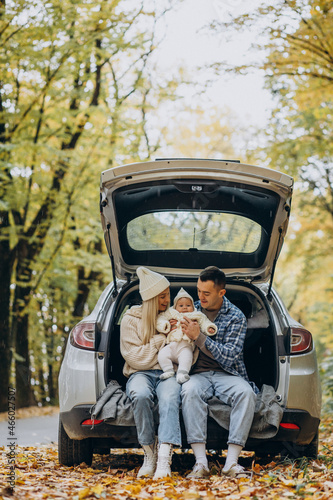 Young family with baby daughter sitting in the back of their car in the autumnal forest © Petro
