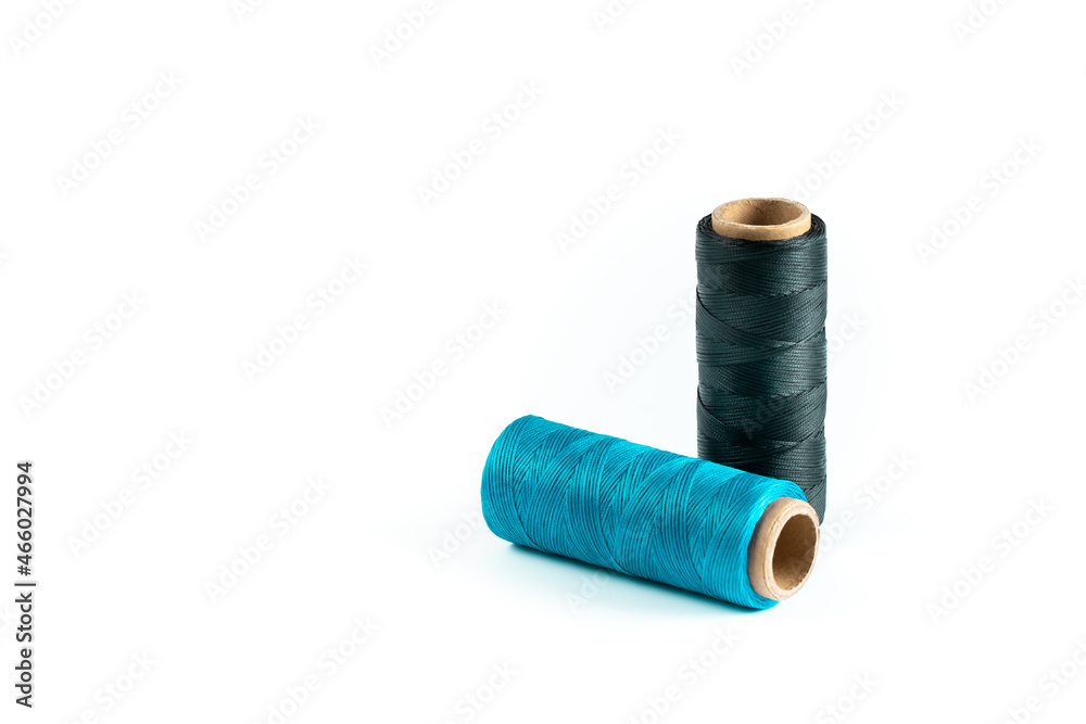 A skein of black and cyan thread. Coils of colored threads on a white background. Waxed sewing thread for leather goods. A skein of black and cyan thread. Coils of colored threads on a white background. Waxed sewing thread for leather goods.