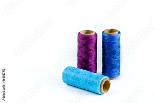 A skein of purple, blue and cyan thread. Coils of colored threads on a white background. Waxed sewing thread for leather goods.